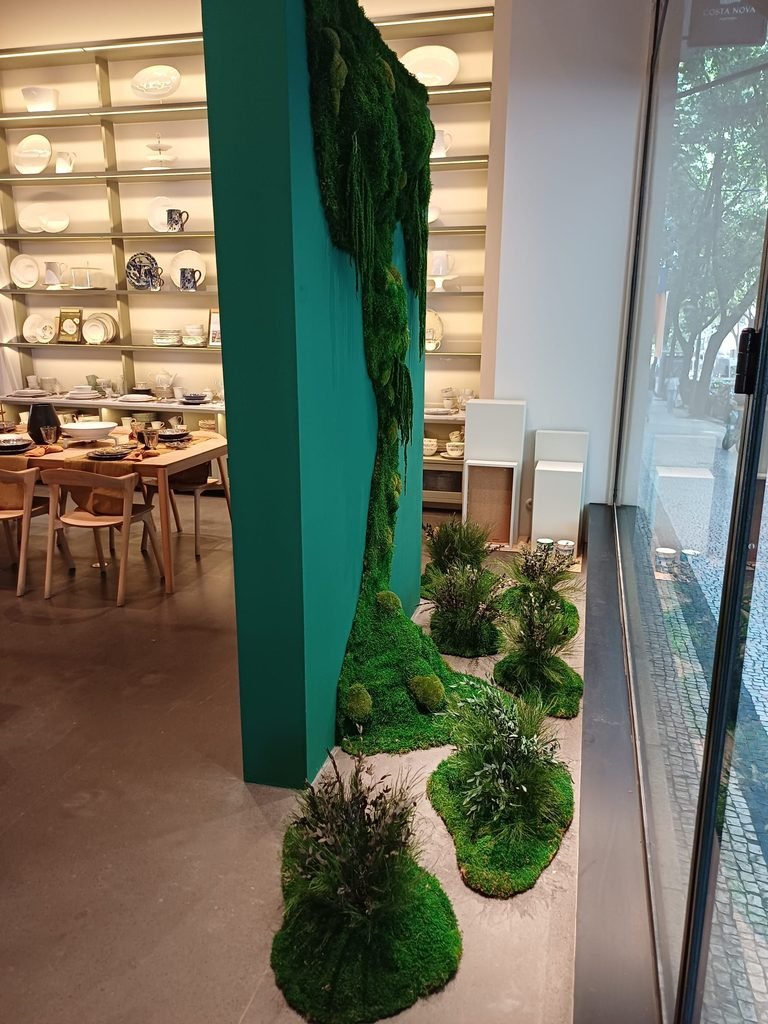 Ilhas de musgo e plantas preservadas aplicadas no chão da montra comercial, criando um ambiente biofílico e de luxo.