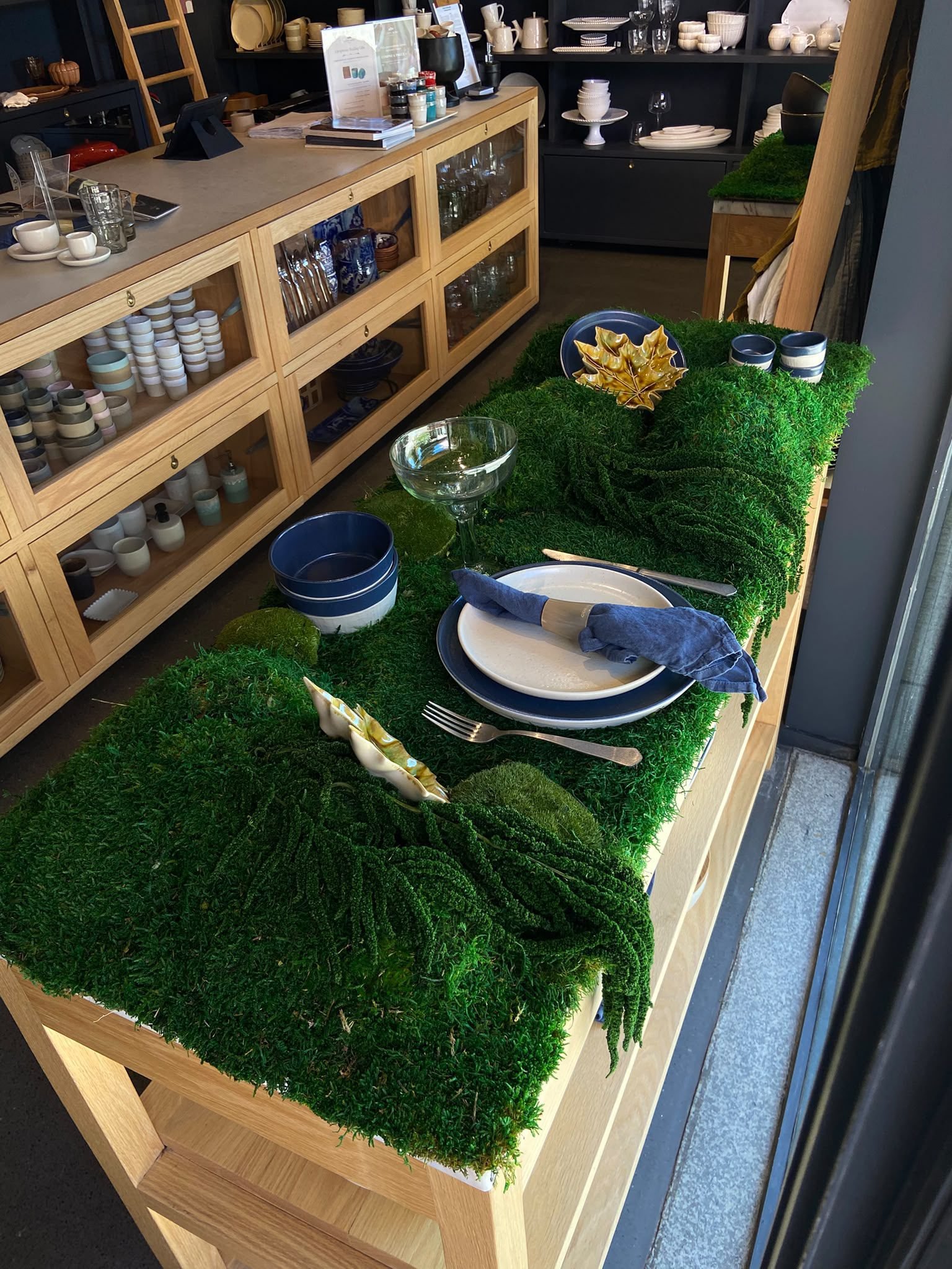 Mesa de exposição na loja Costa
Nova revestida com tapete de musgo preservado MossnArt, destacando peças de cerâmica de luxo.